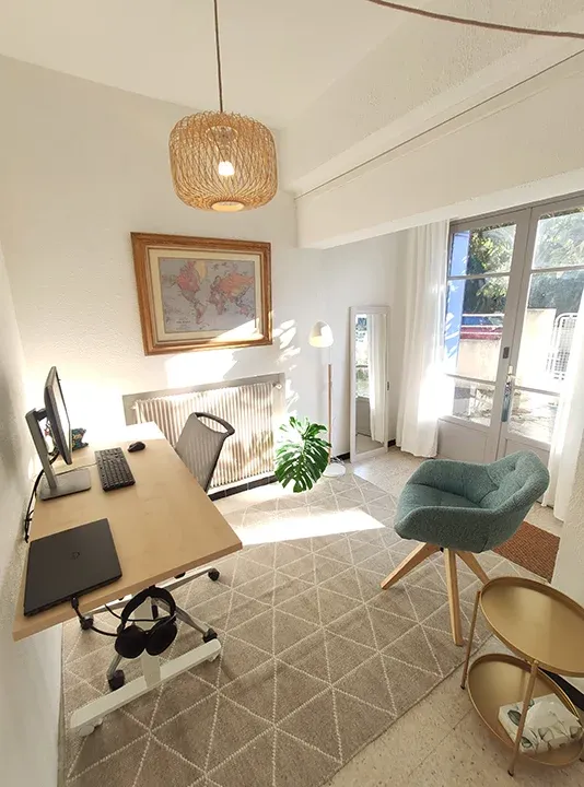 Le cabinet de naturopathie Elise Rouvrais, 42 place du Cèdre à Lunel : bureau, fauteuil et porte-fenêtre ensoleillée
